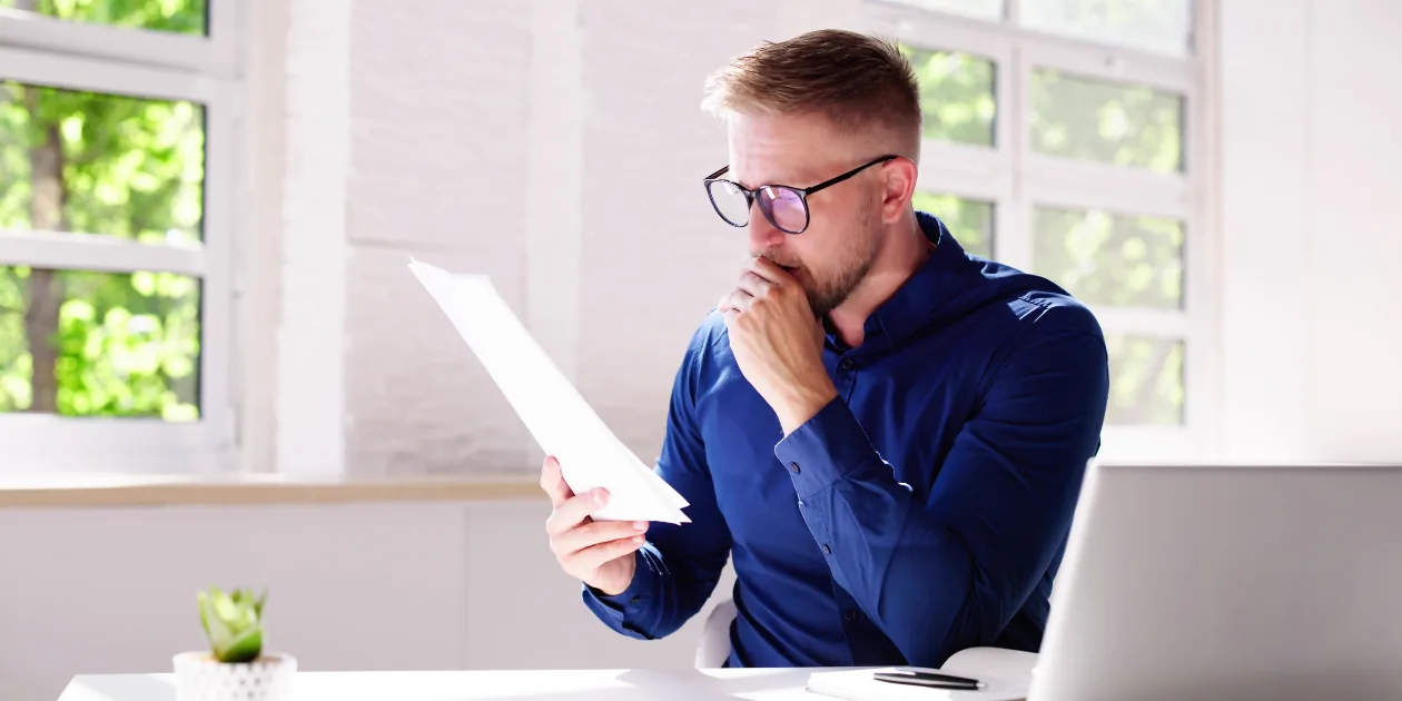 A person reading a Canada visa refusal letter that says the officer is not satisfied you will leave Canada