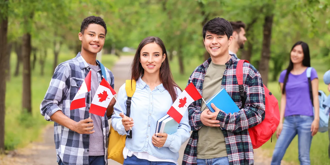 A group of international students holding small Canadian flags, representing the Canada study permit processing time wait